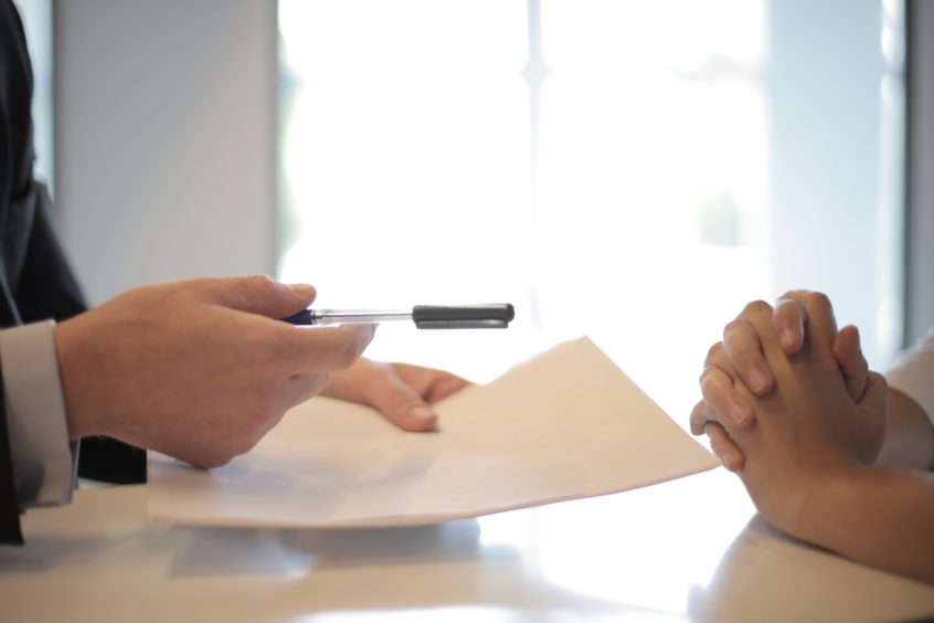 A business person handing over documents and a pen